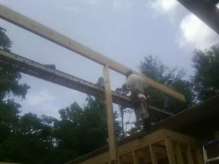 Carpenter setting a ridge beam over a new addition frame — Ice Dam Removal by Roofing Brothers in Bryan