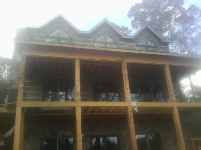 Dormers and porch framing on a large log home under construction — Roof Coating work by our crew in Bryan
